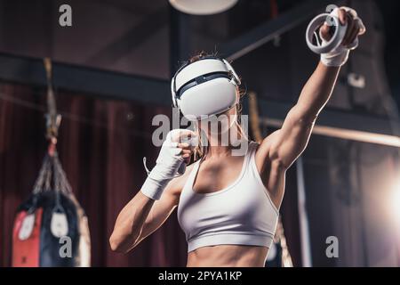 Gli amanti del fitness combattono contro altri membri della palestra indossando occhiali per realtà virtuale durante intensi esercizi di boxe. Imparare e migliorare la tecnologia di boxe Foto Stock