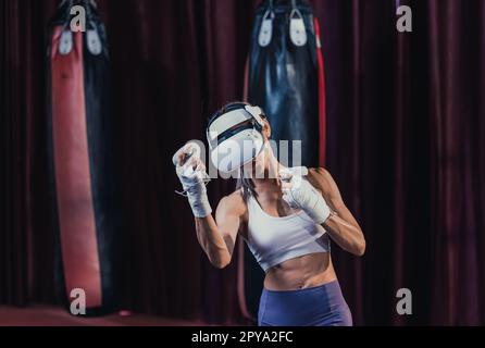 Gli amanti del fitness combattono contro altri membri della palestra indossando occhiali per realtà virtuale durante intensi esercizi di boxe. Imparare e migliorare la tecnologia di boxe Foto Stock