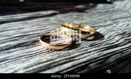 due fedi nuziali dorati su sfondo polo con riflessi dei raggi di sole sullo sfondo Foto Stock