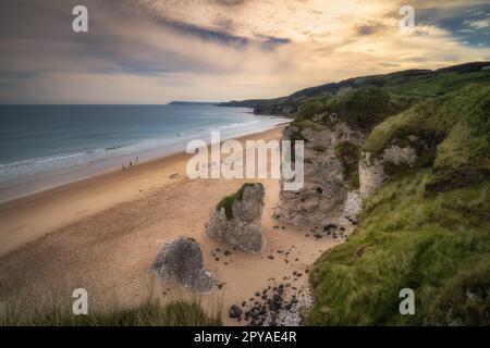 Gente che cammina sulla spiaggia di White Rocks con formazioni di roccia calcarea, Irlanda del Nord Foto Stock