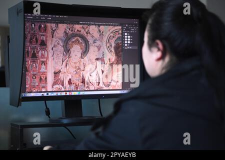 Dunhuang, provincia cinese del Gansu. 25th Apr, 2023. Nian Haili, un tecnico del team di conservazione digitale dell'Accademia Dunhuang, elabora le immagini di un murale a Dunhuang, nella provincia di Gansu della Cina nord-occidentale, il 25 aprile 2023. Un gruppo di giovani tecnici ha cercato di utilizzare la tecnologia digitale per garantire la conservazione permanente e l'uso sostenibile delle reliquie culturali nelle grotte di Mogao, un sito patrimonio dell'umanità dell'UNESCO a Dunhuang. Credit: Notizie dal vivo su Chen Bin/Xinhua/Alamy Foto Stock