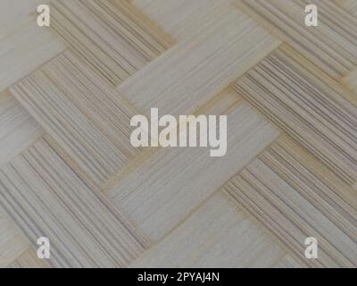 Frammento di pavimento in parquet. Motivo parquet. Interlacciamento di elementi. Superficie in legno, bambù o paglia. Tappetino caldo. Primo piano. Foto Stock