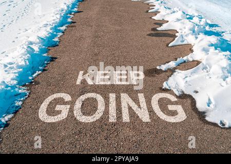 Continua a trasmettere un messaggio motivazionale su asfalto Foto Stock
