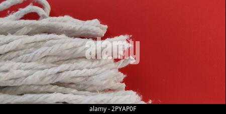 Accessorio per strisciatore di funi in cotone. Il materiale viene strappato con un singolo movimento rotatorio, evita di sporcarsi le mani e riduce i tempi di pulizia. L'ugello in cotone assorbe l'acqua. Sfondo rosso Foto Stock