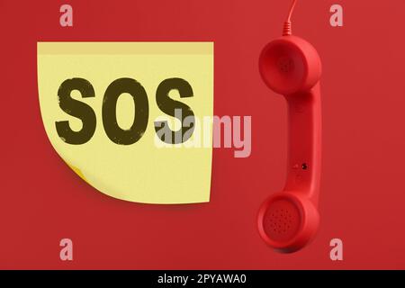 Telefono su sfondo rosso. Chiamata SOS di emergenza Foto Stock