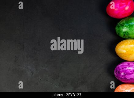 Sfondo elegante con uova di pasqua colorate isolate su sfondo di cemento scuro per il web design. Piano, vista dall'alto, mockup, spazio per fotocopie a soffitto concetto Happy Easter Foto Stock