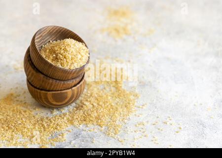 Ciotole in legno con bulgur secco non cotto grano da vicino, spazio per copia. Cibo sano Foto Stock