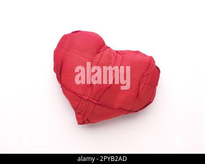 Primo piano di una forma a cuore di tessuto rosso su bianco Foto Stock