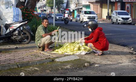 transazione tra venditore di ketupat e buyerin la mattina. Foto Stock