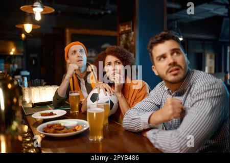 Gruppo di amici preoccupati che guardano la squadra preferita allo sport bar Foto Stock