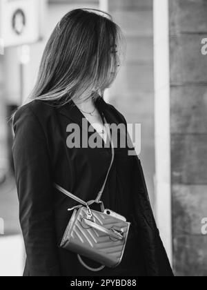 nero e bianco strada ritratto di curvy brunette capelli lunghi piedi misto asiatico razza modello femminile guardando gioioso shopping nel city Foto Stock