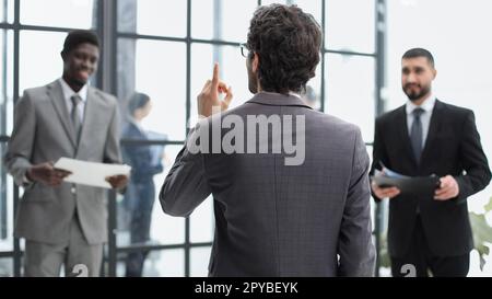 un uomo si alza con la schiena sullo sfondo dei suoi colleghi Foto Stock