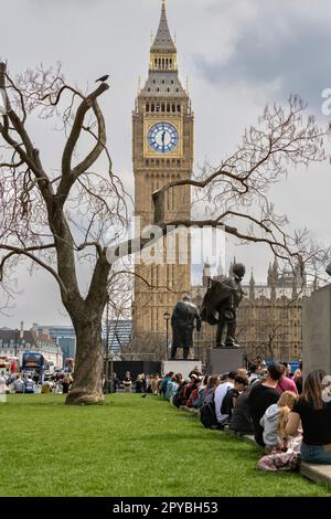 Whitehall London UK persone rilassarsi e sedersi una settimana prima dell'incoronazione di re Carlo III con il Big ben sullo sfondo 30th aprile 2023 Foto Stock