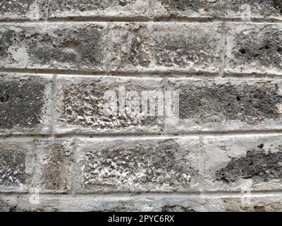 Muratura in pietra invecchiata con le intemperie di una vecchia casa. Antico sfondo murale in mattoni. Vecchi mattoni di pietra graffiati irregolari. Muro dell'edificio turco. Sfondo irregolare di pareti calcaree Foto Stock