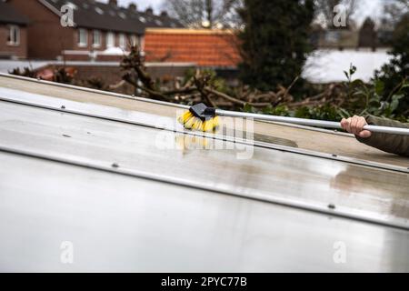 Lavaggio del copricapo pergolato in alluminio. rimuovere le alghe sporche con sapone a spazzola e acqua vicino in giardino da una terrazza casa Foto Stock