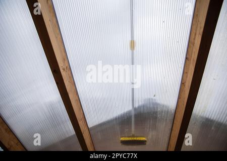 Lavaggio del copricapo pergolato in alluminio. rimuovere le alghe sporche con sapone a spazzola e acqua vicino in giardino da una terrazza casa Foto Stock