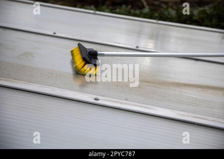 Lavaggio del copricapo pergolato in alluminio. rimuovere le alghe sporche con sapone a spazzola e acqua vicino in giardino da una terrazza casa Foto Stock