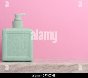 Contenitore dispenser di sapone in plastica su sfondo rosa, cosmetici Foto Stock