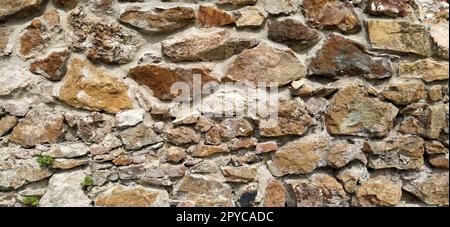 Muro di pietra. Grandi ciottoli impilati in colori caldi. Torre a Kula, Serbia. Foto Stock