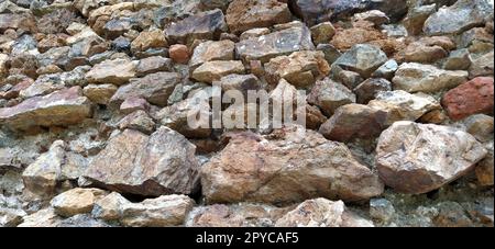 Muro di pietra. Grandi ciottoli impilati in colori caldi. Torre a Kula, Serbia. Foto Stock