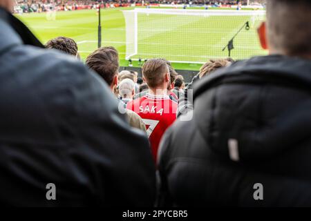 Giovane uomo in folla ad una partita di calcio con la maglia Saka, l'Arsenal Football Club, lo stadio Emirates di Londra Foto Stock