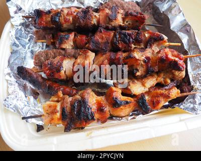 Carne grigliata in confezioni monouso e fogli di alluminio, consegnata da un ristorante. Consegna di cibo a domicilio da ristoranti e caffetterie. Kebab shish e carne di pollo, maiale e agnello Foto Stock