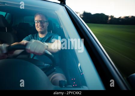 Bel giovane pilota che guida la sua auto velocemente e in sicurezza su strada (immagine sfocata del movimento) Foto Stock