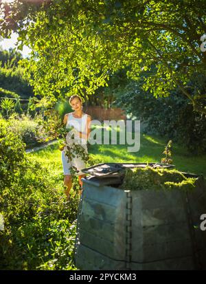 Piuttosto, giovane donna giardinaggio nel suo giardino, il taglio di rami, preparare il frutteto per l'inverno Foto Stock