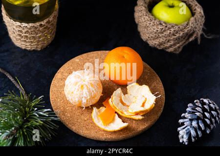 Natale di Capodanno ancora ramo di vita di pino accanto ai coni tangerini su sfondo nero Foto Stock