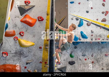 bouldering su una parete artificiale di arrampicata Foto Stock