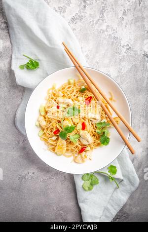 Mescolare gli spaghetti fritti con il pollo e le verdure in un recipiente bianco Foto Stock