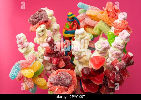 Variazione di frutta colorata gengive dolci spiedato orsacchiotto gommoso orsi marshmallow su spiedini di legno isolato su uno sfondo rosso magenta Foto Stock