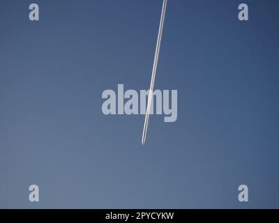 Il sentiero di un aereo che vola nel cielo. Cielo blu sera. Emissioni di cherosene o di combustibile per missili eptilici. Concetto ambientale. Trasporto aereo di affari e di passeggeri. Foto Stock