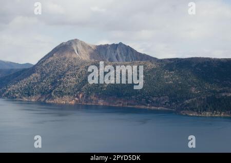 Monte Kamui che sorge sopra il lago Mashu. Foto Stock