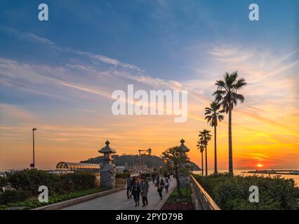 kanagawa, enoshima - 25 2022 dicembre: Tramonto sul ponte di Enoshima Ohashi con i turisti che passeggiando verso l'isola di Enoshima adornata da draghi scolpiti Foto Stock