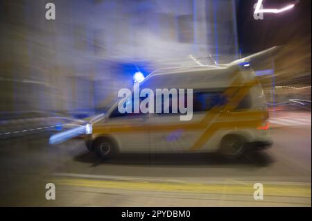 Ambulanza paramedica in movimento sfocato corse ambulanza per rispondere alla scena di un'emergenza con luce blu lampeggiante in centro. Foto Stock