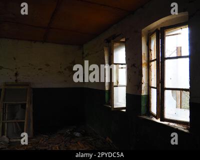 Finestre spaventose. In una casa abbandonata. Vista delle finestre rotte senza tenda. Scena grunge. La luce splende attraverso vecchie strutture in legno con vetri rotti. Il concetto di abbandono e inutilità Foto Stock