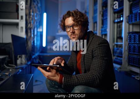 Tecnico IT maschile che lavora in una sala server con tablet Foto Stock