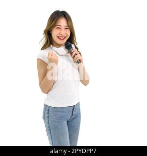 Giovane donna asiatica con t-shirt bianca e jean in piedi sorridente con le cuffie sul collo, cantando con il microfono. Ritratto su sfondo bianco con luce da studio. Isolato Foto Stock