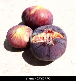 Il fico o o albero di fico comune, o Ficus carica è una pianta decidua subtropicale del genere Ficus della famiglia dei gelsi. Frutti di fico viola maturi su uno sfondo chiaro. Cibo sano Foto Stock