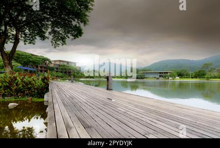 Ponte di legno sul lago in un hotel sostenibile vicino alla montagna. Hotel di lusso nella foresta. Hotel verde di lusso nella valle. Rifugio nella natura. Hotel con vista sul lago. Destinazioni di viaggio per una mente di riposo. Foto Stock