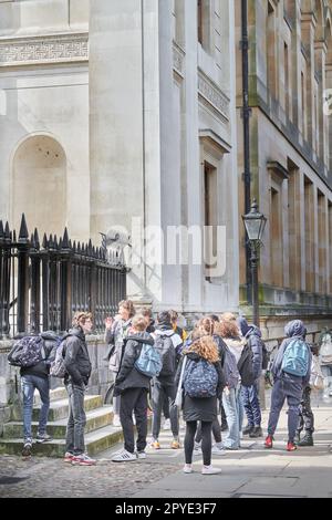 Un gruppo di giovani turisti con guida fuori dal Senato House, Università di Cambridge, Inghilterra. Foto Stock