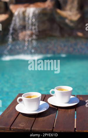 Due tazze di caffè sul tavolo vicino alla piscina Foto Stock