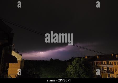 Tempesta notturna sulla città. Flash di fulmini e nuvole basse. Tuono e fulmini. Concetto di elemento naturale, cambiamento climatico e previsioni meteorologiche. Scarico di elettricità nel cielo. Foto Stock