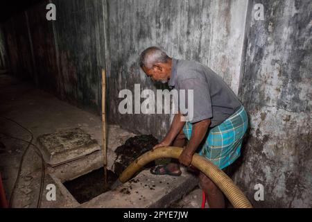 Bangladesh, Khulna. Un uomo svuota i fanghi fecali da un serbatoio settico a tarda notte in una moschea. Marzo 19, 2017. Solo per uso editoriale. Foto Stock