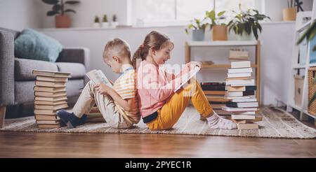 Due bambini seduti sul pavimento in camera e leggendo libri. Foto Stock