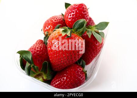 Fragole mature in una confezione di plastica su sfondo bianco. Deliziose bacche fresche in un contenitore per la vendita ai clienti. Mantenere il cibo fresco. Cibo sano, vitamine e microelementi. Foto Stock