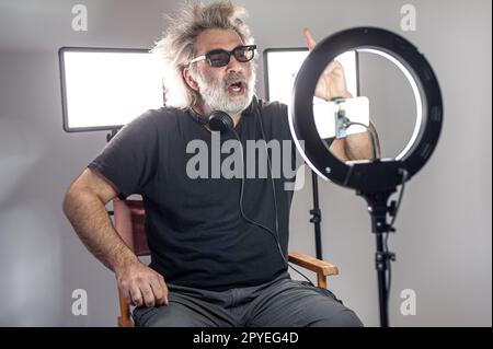 Radio host, affascinante influencer, registra uno spettacolo dal vivo con materiale e attrezzature per la fotocamera. Foto Stock