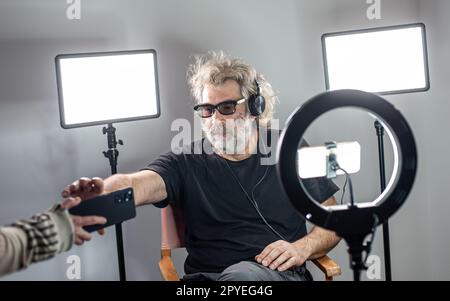 Radio host, affascinante influencer, registra uno spettacolo dal vivo con materiale e attrezzature per la fotocamera. Foto Stock