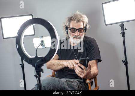 Radio host, affascinante influencer, registra uno spettacolo dal vivo con materiale e attrezzature per la fotocamera. Foto Stock